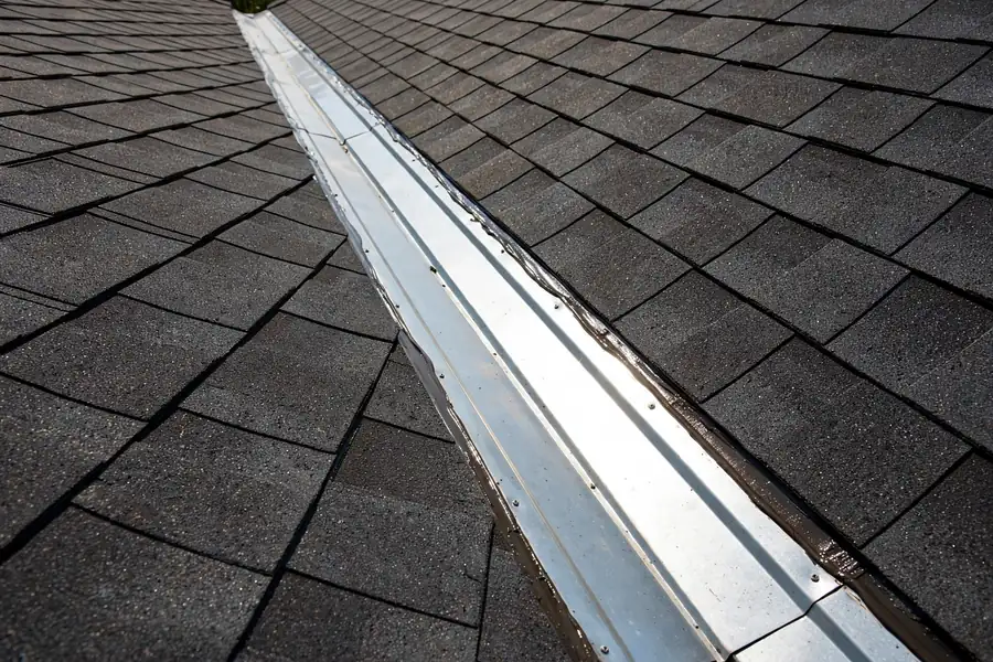 Roof valley with damaged flashing and water-stained shingles before leak repair